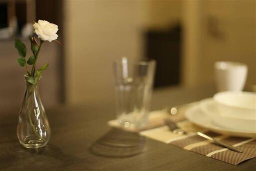 Close-up view of a dining table with a flower vase, glasses, and tableware