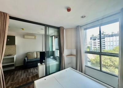 Bedroom with glass sliding doors, view of adjacent living room area, large windows with city view, and wooden floors