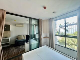 Bedroom with glass sliding doors, view of adjacent living room area, large windows with city view, and wooden floors