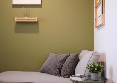 Modern living room corner with green accent wall and a grey couch