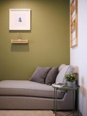 Modern living room corner with green accent wall and a grey couch