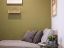 Modern living room corner with green accent wall and a grey couch