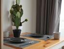 Small dining area with a table set for two and a potted cactus