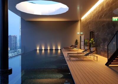 Modern indoor swimming pool with lounge area in a high-rise building