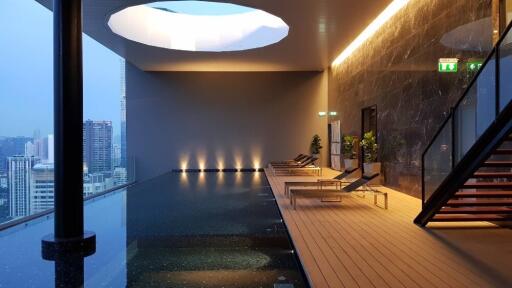 Modern indoor swimming pool with lounge area in a high-rise building
