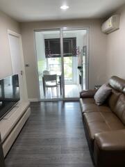 Contemporary living room with leather sofa and glass doors to a bright kitchen