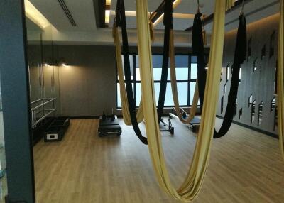 A spacious gym with exercise equipment and aerial yoga hammocks