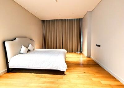 Spacious master bedroom with a double bed and large window with curtains.