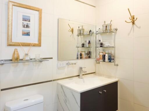 Modern bathroom with framed art, vanity, and glass shelves