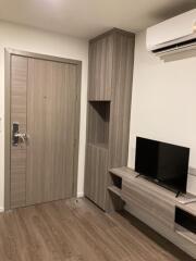 Living room with wooden flooring, a door, built-in TV stand, and air conditioner