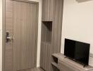 Living room with wooden flooring, a door, built-in TV stand, and air conditioner