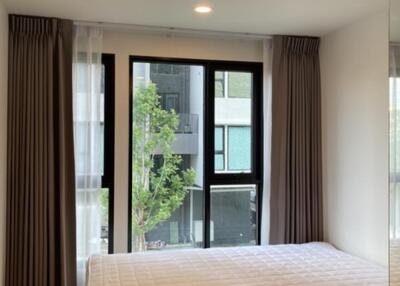 A modern bedroom with a large bed and floor-to-ceiling windows providing natural light.