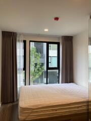 A modern bedroom with a large bed and floor-to-ceiling windows providing natural light.