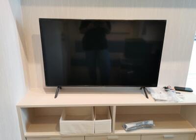 Living room with mounted flat-screen TV and storage shelf