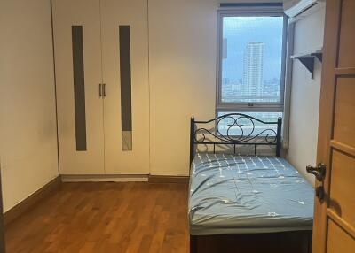 Small bedroom with wooden flooring, a single bed, a built-in closet, and a window with city view.