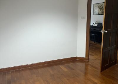 Empty room with wooden flooring and open door leading to another room