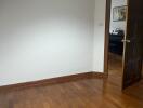 Empty room with wooden flooring and open door leading to another room