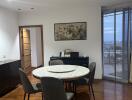 Dining area with round table and chairs, wooden floor, and a view