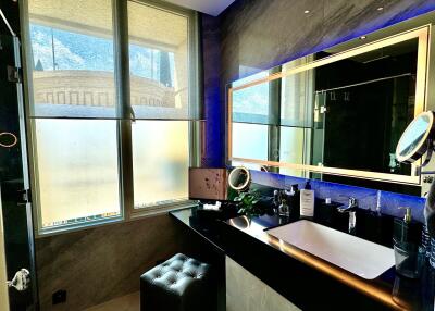 Modern bathroom with large windows, a lit mirror, and a sleek sink area