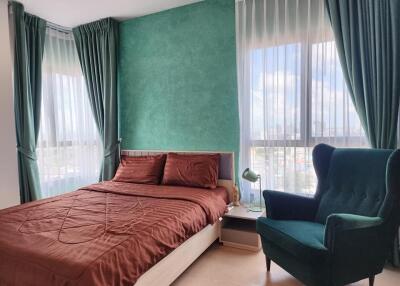 Bright and modern bedroom with large windows, green accent wall, and comfortable furnishings