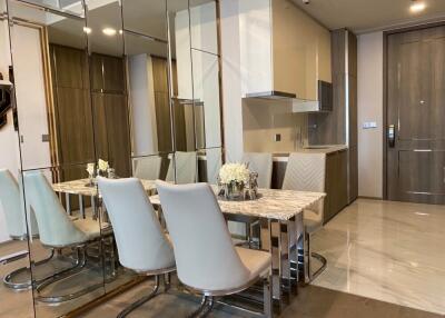 Modern dining area with marble table and chairs next to a compact kitchen
