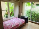 Bedroom with large window and sliding glass door, featuring a pink bedspread