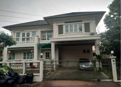 Front view of a two-story house with a gated driveway and a parked car