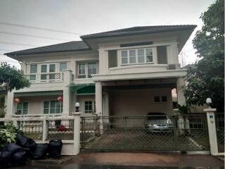 Front view of a two-story house with a gated driveway and a parked car