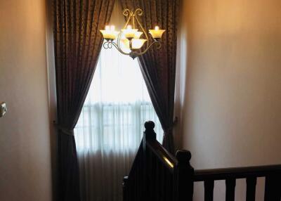 Staircase with chandelier and curtained window