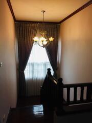 Staircase with chandelier and curtained window