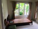 Bedroom with large window, empty bed frame and curtains