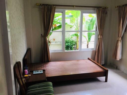 Bedroom with large window, empty bed frame and curtains