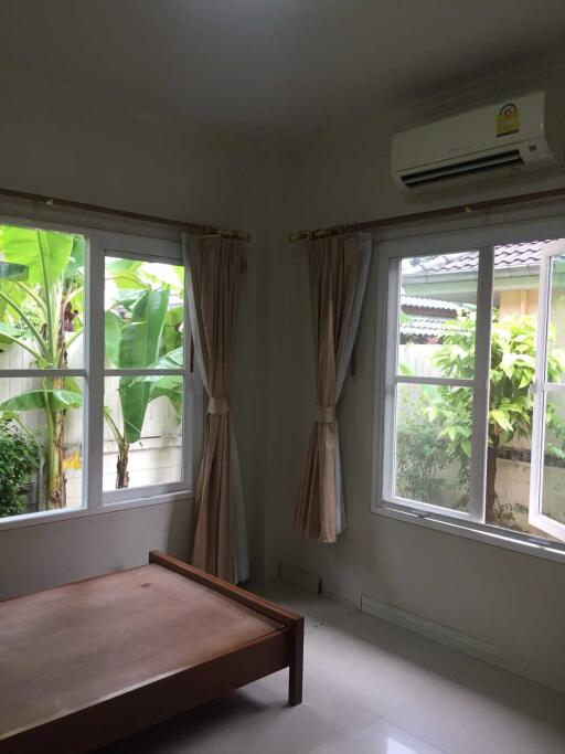 Bedroom with windows showing a garden view and air conditioning