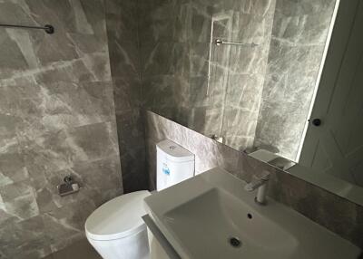 Modern bathroom with marble tiles, sink, and toilet