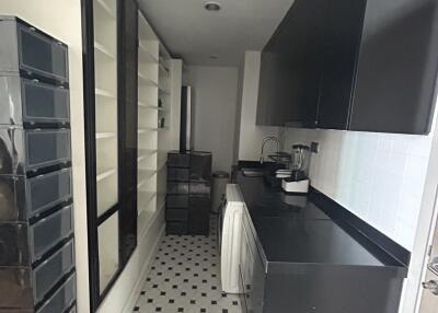 Compact modern kitchen with black and white cabinets, washing machine, and geometric tile flooring