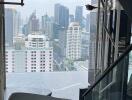 view of cityscape from high vantage point inside a building with a modern staircase