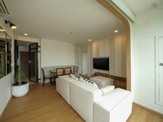 Spacious modern living room with white couch, TV, and dining area