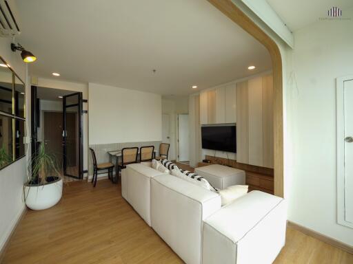 Spacious modern living room with white couch, TV, and dining area