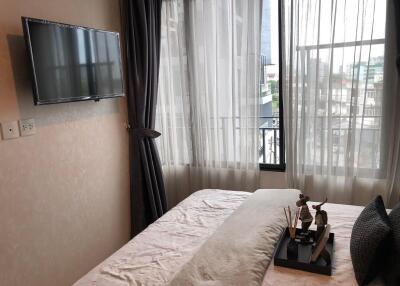 Bedroom with a window, mounted TV, and decorative items