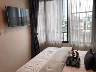 Bedroom with a window, mounted TV, and decorative items