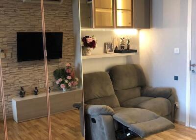 Living room with mirrored wardrobe, grey recliner, wall-mounted TV, and air conditioning