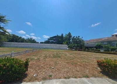 Spacious vacant lot with clear sky and surrounding greenery