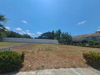 Spacious vacant lot with clear sky and surrounding greenery