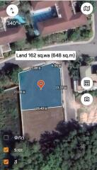 Aerial view of a land plot with boundary measurements and a map marker