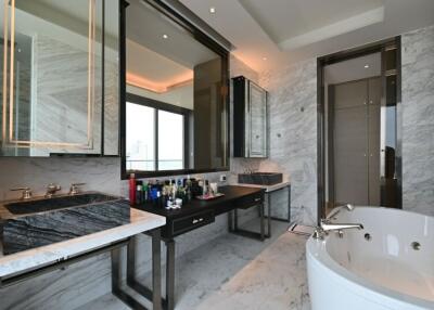 Luxurious bathroom with dual sinks, marble finishes, and a bathtub