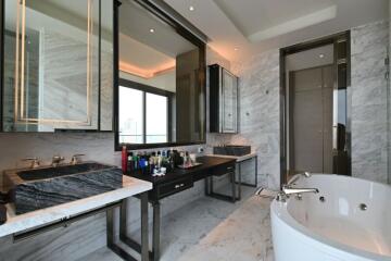 Luxurious bathroom with dual sinks, marble finishes, and a bathtub