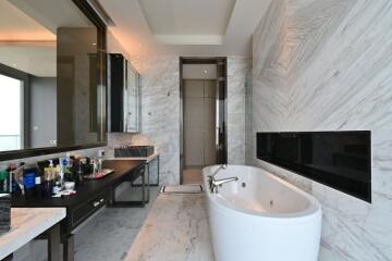 Luxury modern bathroom with marble walls, a freestanding bathtub, and a large mirror