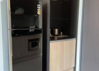 Modern kitchen with a black refrigerator and a small counter with shelving.