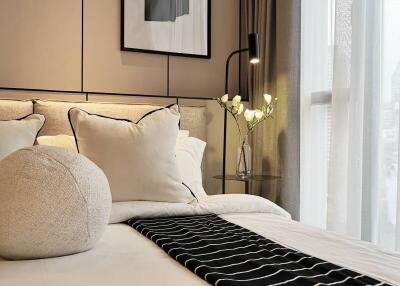 Modern bedroom with cozy bed, decorative pillows, and bedside table with a lamp and flowers