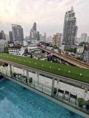 Modern urban building with rooftop greenery and pool overlooking cityscape